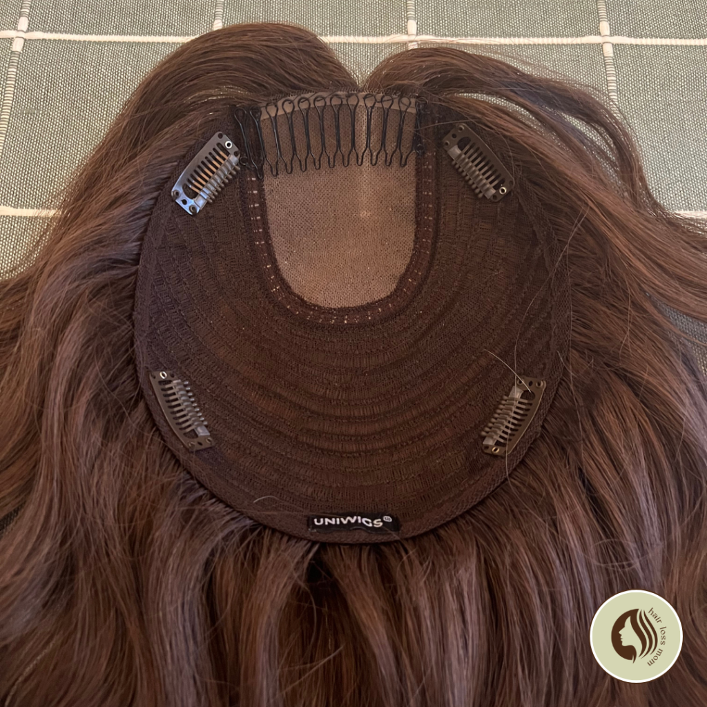 The inside of a uniwigs Courtney hair topper, showing 4 clips and a comb. 